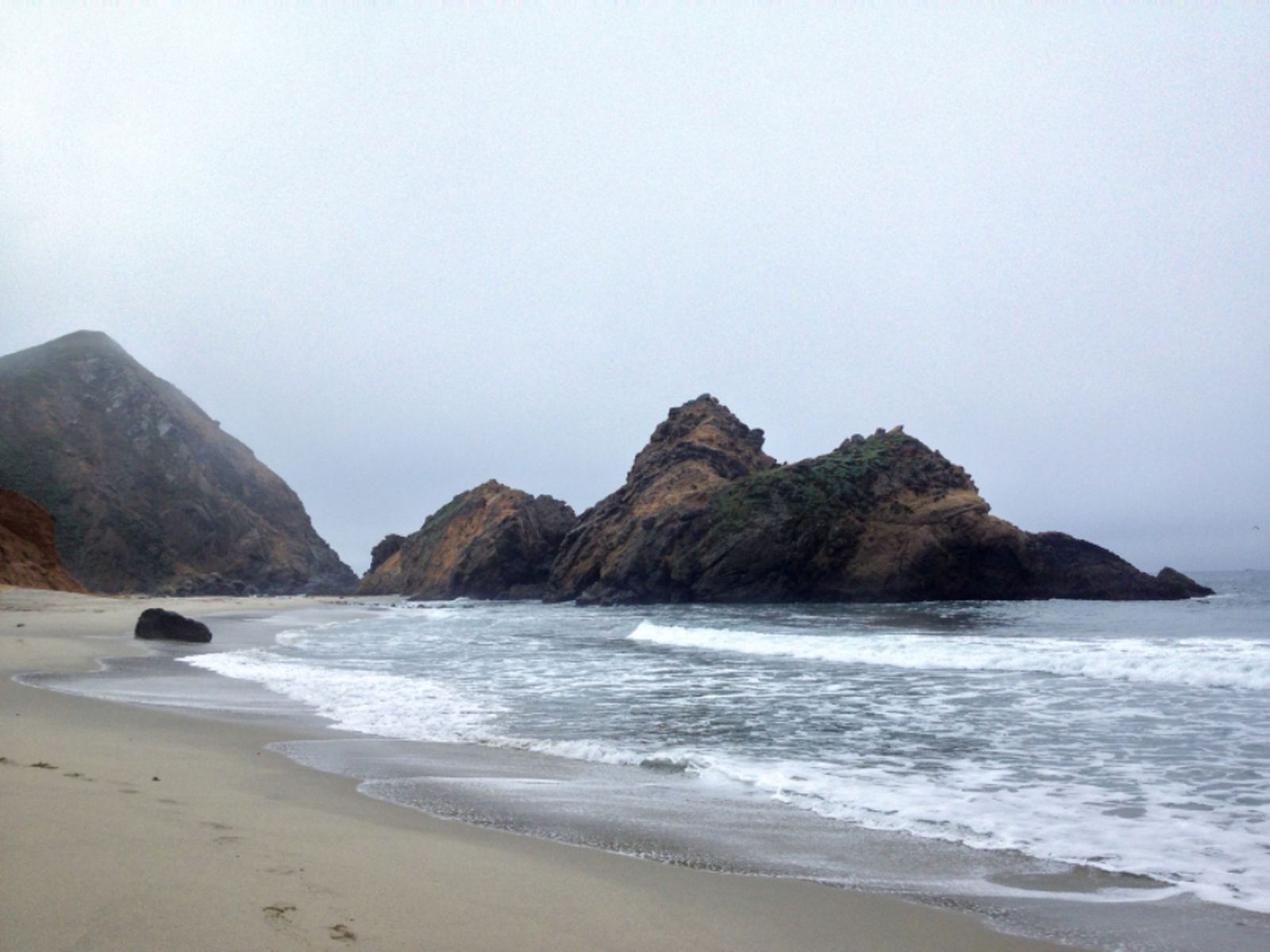 Sea stacks standing in soft fog off a quiet stretch of coast