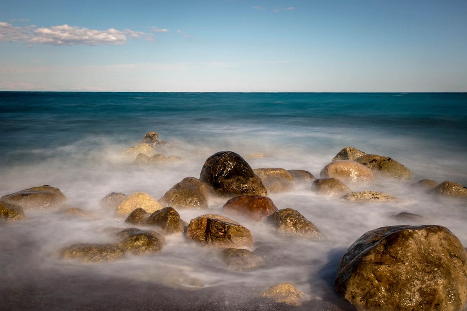 Sea mist moving over dark rocks at the edge of the tide